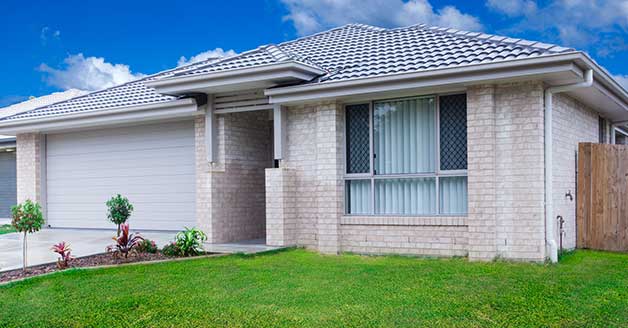 Modern residential home with a well-maintained lawn, featuring a brick exterior, large windows, and a garage, symbolizing effective sump pump installation and repair services by The Plumbing Dr in Arlington.